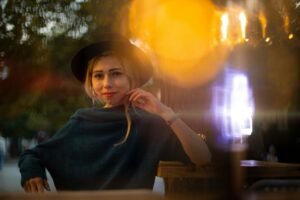 Female portrait of beautiful young lady in black hat in evening city street park walking district immersive romantic atmosphere